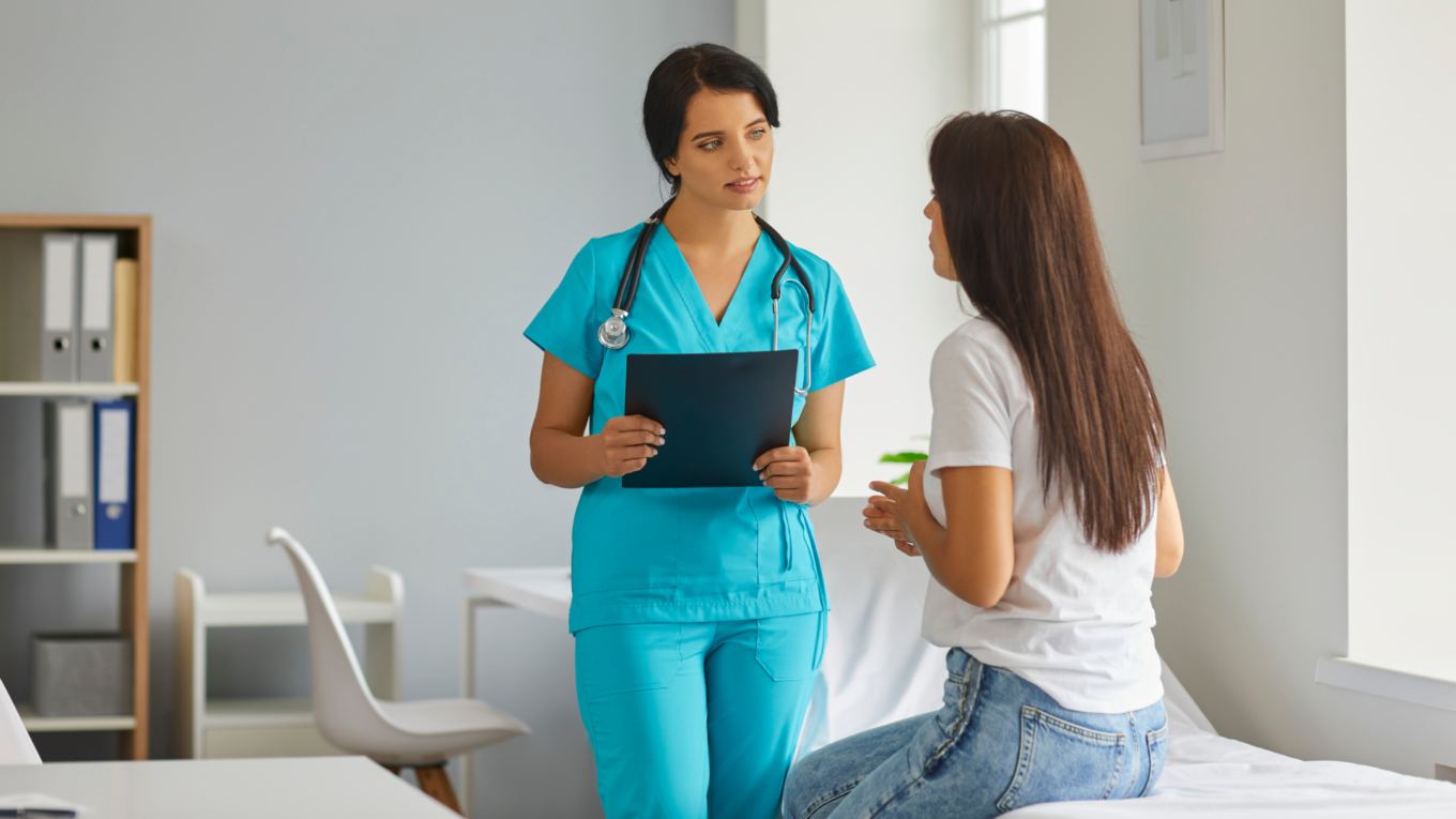 Fachperson für Psychiatriepflege HFP sitzt mit Patientin im Krankenzimmer.